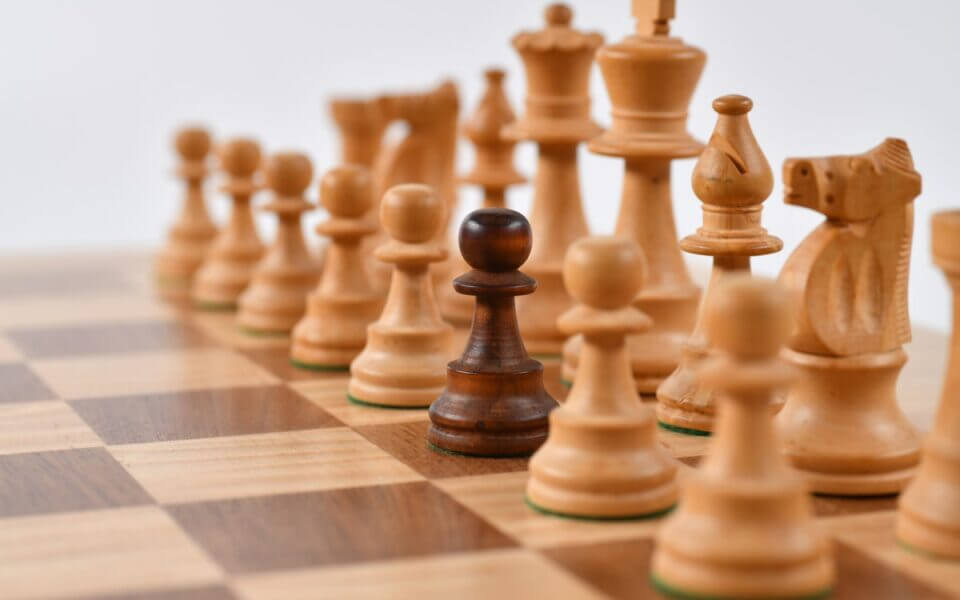 A picture of white chess pieces with a stand-out black pawn