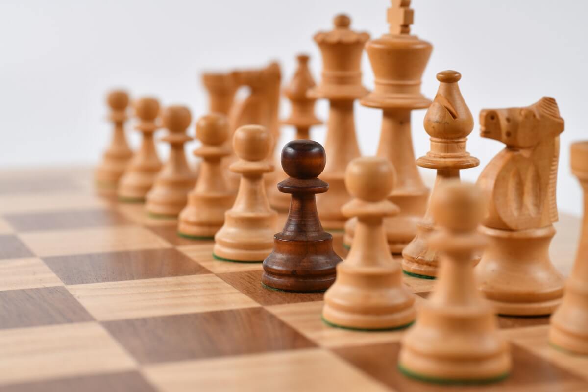 A picture of white chess pieces with a stand-out black pawn